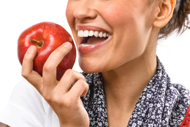 Smiling woman about to bite a red apple